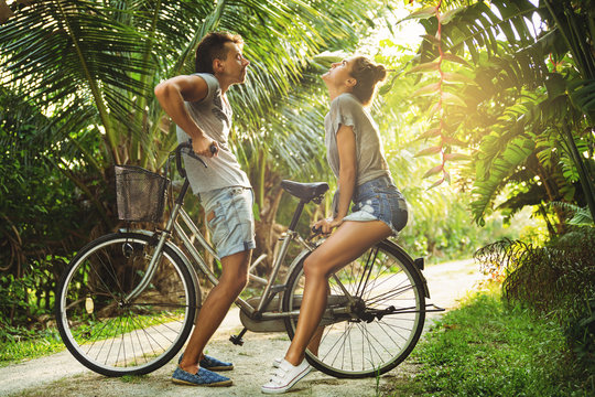 Young couple is riding a vintage bicycle on the country road in tropical country