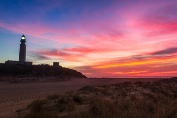 Perfect landscape with Trafalgar lighthouse on empty Zahora beach at splendid colorful sunset in Cadiz, Andalusia. Magic twilight, iconic landmark, tourism attraction, summer holidays concepts
