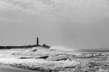 Trafalgar lighthouse silhouette and high contrast light on rough sea in Cadiz province, Spain. Wild...