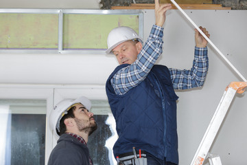 Contractor on stepladder talking to colleague on the ground