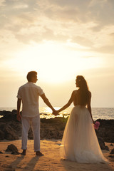 Wedding on the beach - Young married couple holding hands
