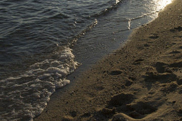 Soft wave of the sea on the sandy beach at sunset.