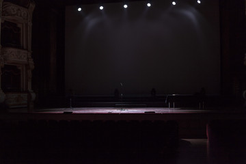 A theatrical stage under spot lights in the darkness.
