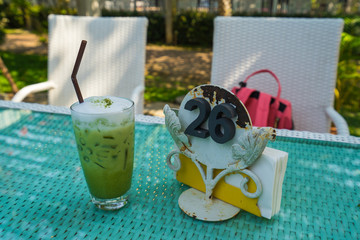 Ice green tea with milk foam on the table number twenty six.