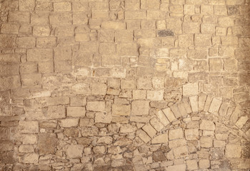 An ancient wall made of stone, irregular but compact rocks forming patterns.
