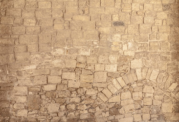 An ancient wall made of stone, irregular but compact rocks forming patterns.
