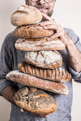 Pile of rustic crusty breads in baker man's hands