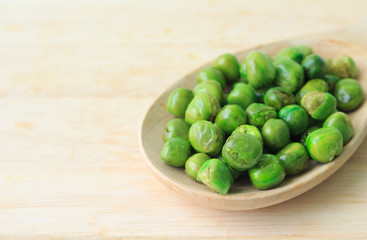 green peas on plate and wooden