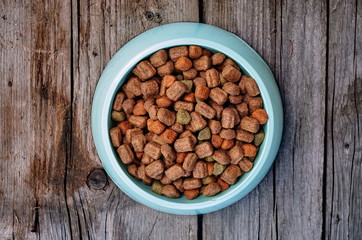 Pet Food In Bowl On Wooden vintage Background. Dry dog food in bowl on wooden vintage background top view.