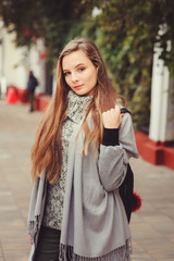 street style portrait of young beautiful happy girl walking in autumn city with trendy leather backpack