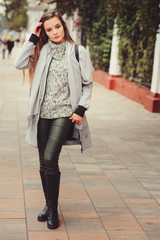 street style portrait of young beautiful happy girl walking in autumn city with trendy leather backpack