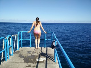 woman jumping from pier to blue ocean