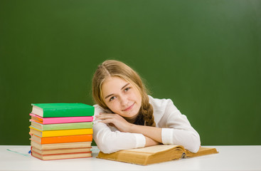 Happy girl lying on the book on the background of a school board