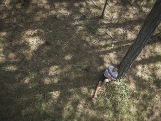 young man in casual sitting dreaming under the tree in the forest aerial top view