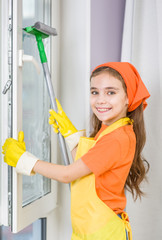 Happy little girl washes the window with a scraper