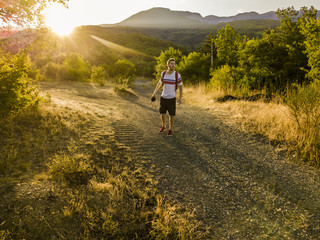 young man with backpack walking on a mountain road tourist nature concept