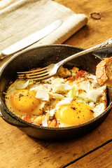 Traditional rustic fast breakfast - fried eggs with tomatoes in a frying pan
