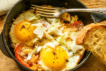 Traditional rustic fast breakfast - fried eggs with tomatoes in a frying pan