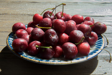Cherry berries in a blue gzhel plate on a  wooden background