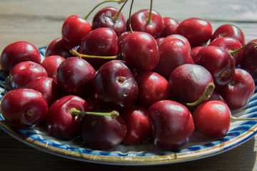 Cherry berries in a blue gzhel plate on a  wooden background