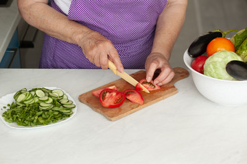 Cropped image of old woman cutting vegetables in the kitchen. Healthy food.