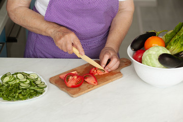 Cropped image of old woman cutting vegetables in the kitchen. Healthy food.