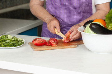 Cropped image of old woman cutting vegetables in the kitchen. Healthy food.