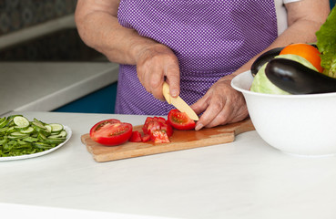 Cropped image of old woman cutting vegetables in the kitchen. Healthy food.