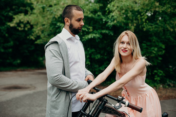 Fototapeta na wymiar Close up of loving gentle couple riding on bike. People in love in park on sunset clodly time. Pretty girl with long hair and boy with bike. Time to kiss. Couple having a bicycles race into the nature