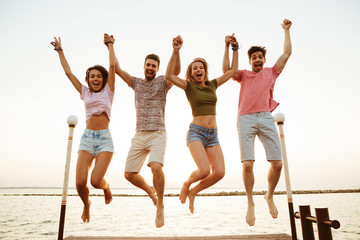 Obraz premium Friends loving couples jumping outdoors on the beach.