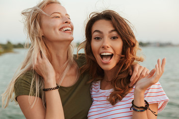 Women friends hugging outdoors on the beach.