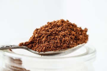 Ground natural coffee heap in a metal spoon closeup shot