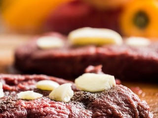 Beef stake close up with seasonings and garlic on top
