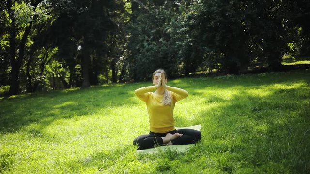 woman sitting in the lotus position doing yoga exercises outdoor in park health lifestyle fitness meditation relax body fit green nature care sun grass morning girl pose fresh meditate active sport