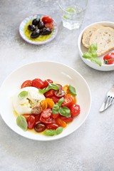 
    Mozzarella and cherry tomatoes salad with fresh basil and olives. 