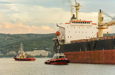 Tug boat entering the harbor with big cargo boat.