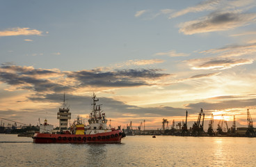 Fototapeta premium Tug boat entering the harbor with big cargo boat.