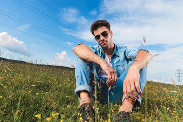 attractive casual man with glasses resting in a grass field