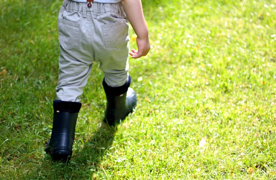 dziecko chodzi po trawie w kaloszach po deszczu 