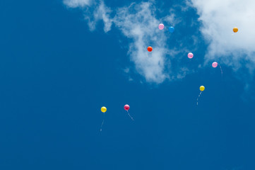 Celebratory background, colorful festive balloons in the sky. Festive background with space for text. Multicolored beautiful balloons fly away into the blue sky