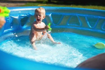 Baby kids playing at baby pool at backyard. Kids pool having fun. Summer day at home. Family time.