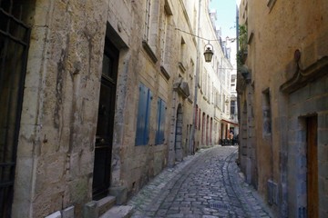 Fototapeta na wymiar Antique narrow street with old pavement from medieval period. Strong mediterranean culture.