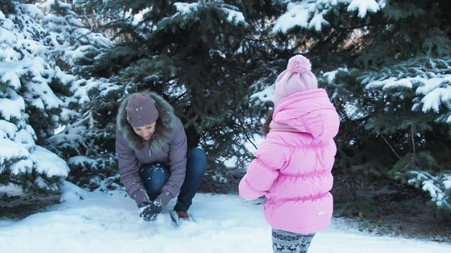 The family plays snowballs. A child with mother is playing with snow.