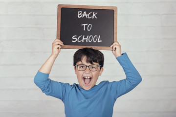 back to school, happy child with a blackboard on brick background