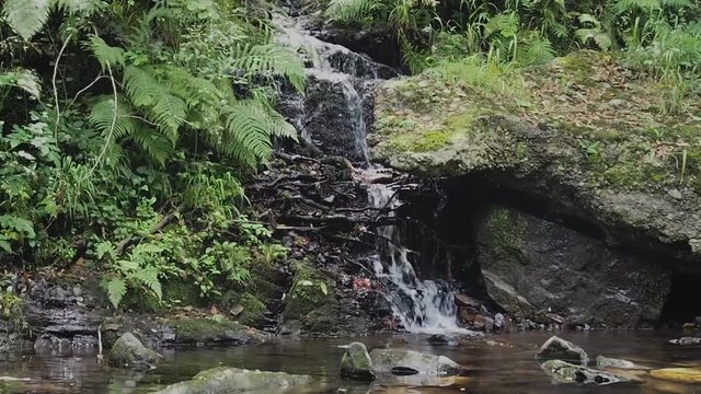 Peque&ntilde;a cascada de agua cayendo en c&aacute;mara lenta