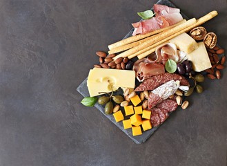 Mediterranean appetizers. Platter with tapas selection: jamon, cheese variety, olives and nuts.   Overhead view, copy space.