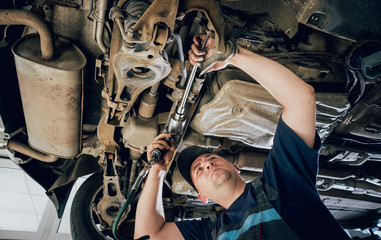 Car mechanic repair car suspension of lifted automobile at repair service station