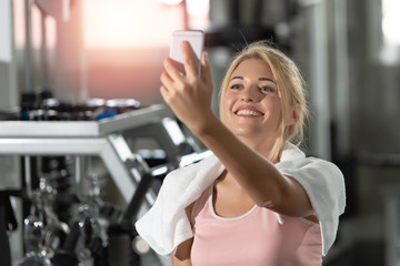 Caucasian young women are smile happy with a Smartphone, taking pictures of yourself after work out exercising in gym. Technology and Living healthy lifestyle concept..