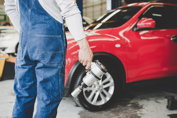 Obraz premium The rear of the car mechanic holding the device changing tyre of car. Repair service..