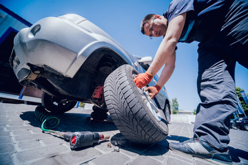 Professional car mechanic replace tire on wheel.
